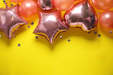 Colorful balloons and confetti on yellow background, flat lay. Space for text