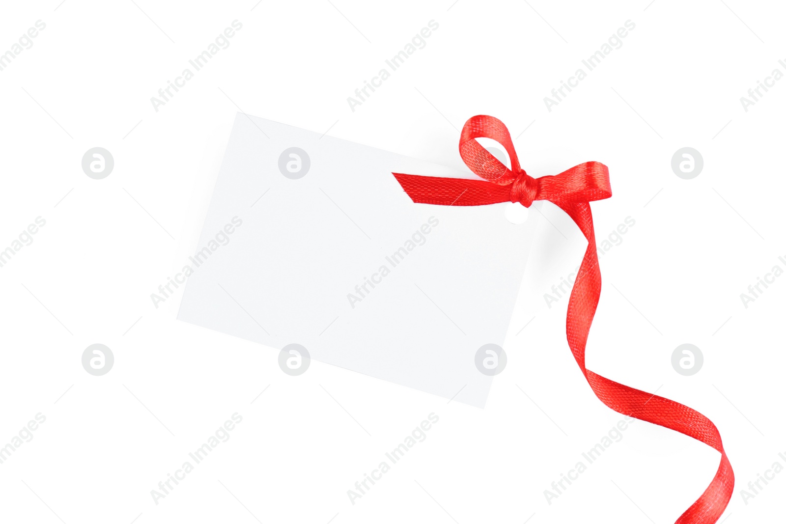 Photo of Blank gift tag with red satin ribbon on white background, top view