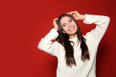 Image of Pretty woman wearing warm sweater on red background 