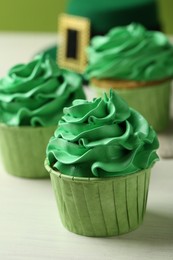 Photo of St. Patrick's day party. Tasty cupcakes with green cream on white table