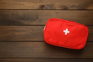 First aid kit bag on wooden table, top view. Space for text