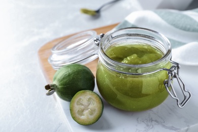 Photo of Feijoa jam and fresh fruits on white table, closeup