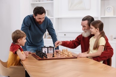 Family playing chess together at table in room