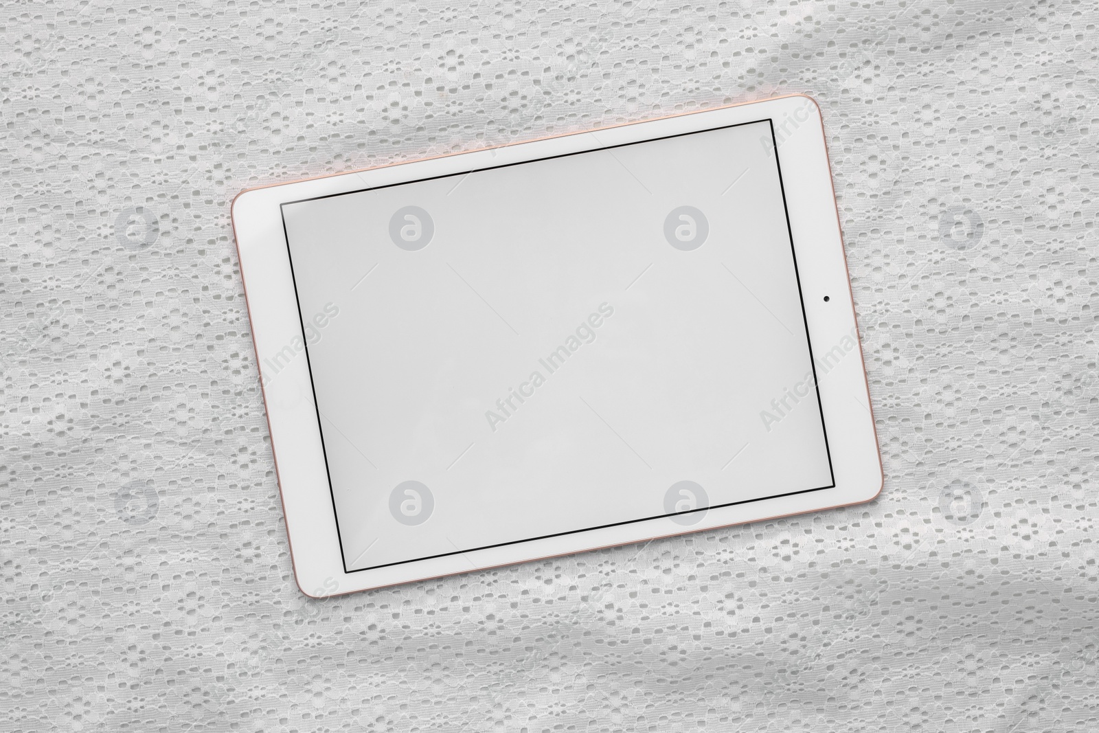 Photo of Modern tablet on white fabric, top view. Space for text