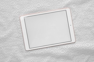 Modern tablet on white fabric, top view. Space for text