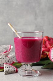 Photo of Delicious pitahaya smoothie and fresh fruits on light grey table