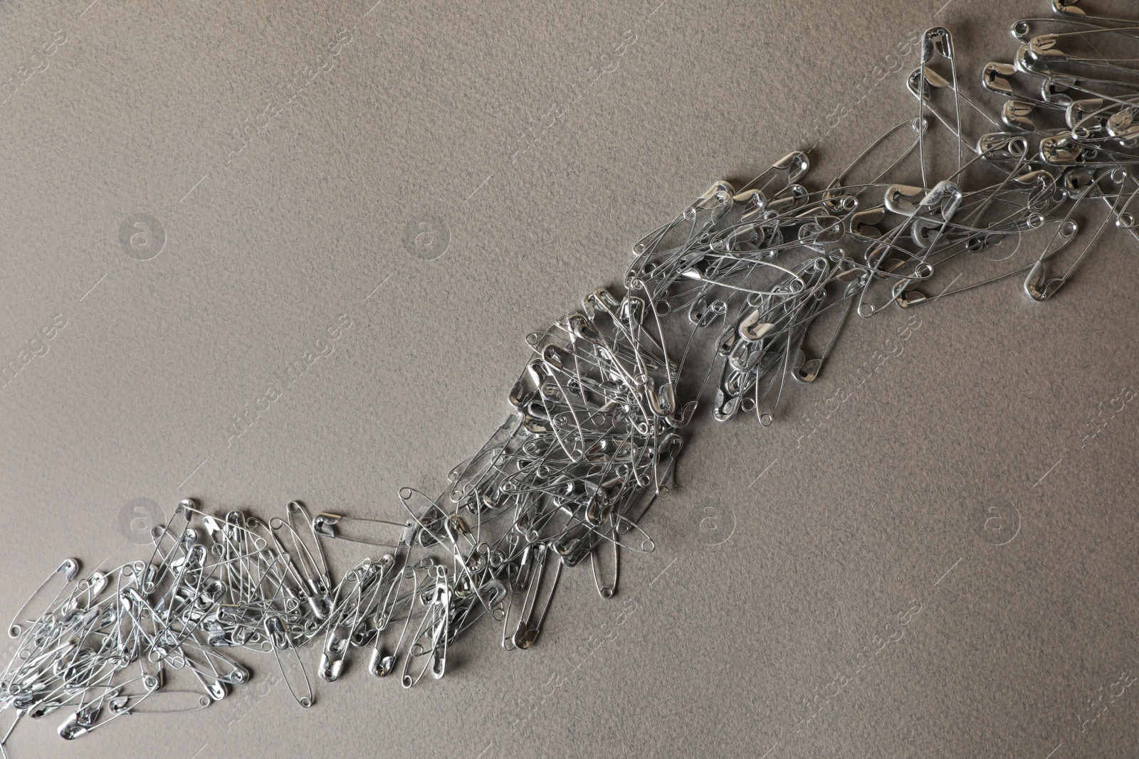 Photo of Many safety pins on light grey textured background