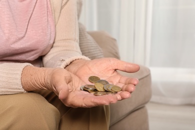 Elderly woman with pile of coins indoors, closeup