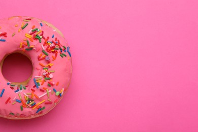Sweet glazed donut decorated with sprinkles on pink background, top view and space for text. Tasty confectionery