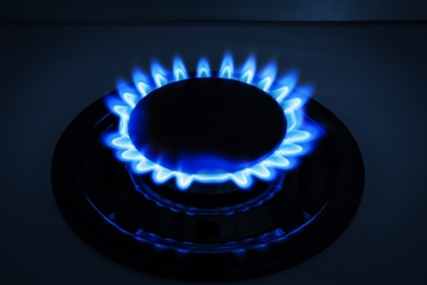 Photo of Gas burner of modern stove with burning blue flame at night