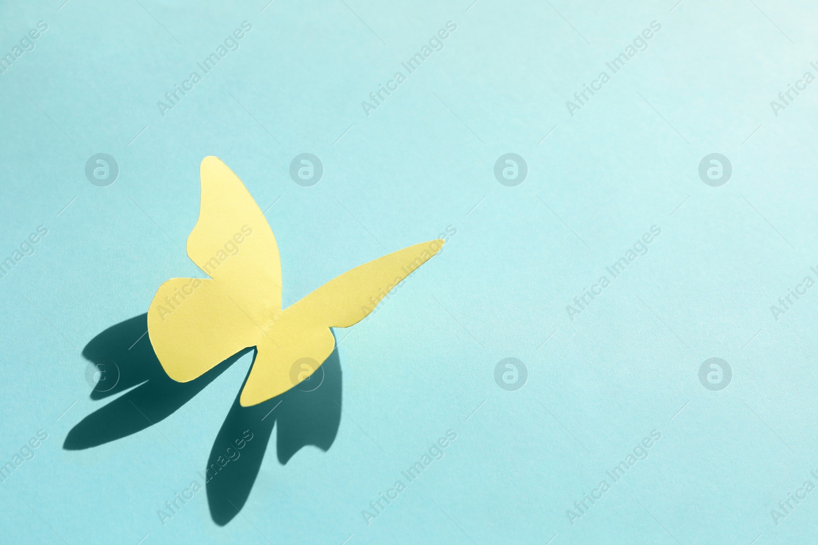 Photo of Yellow paper butterfly on turquoise background, space for text