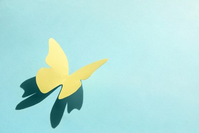 Photo of Yellow paper butterfly on turquoise background, space for text