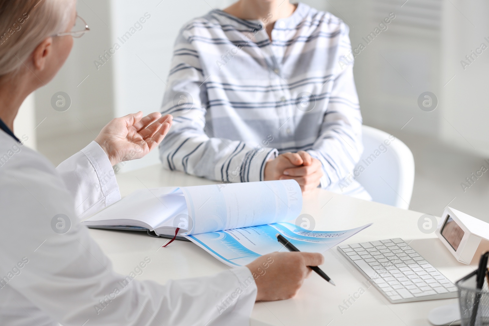 Photo of Doctor consulting patient at desk in clinic, closeup