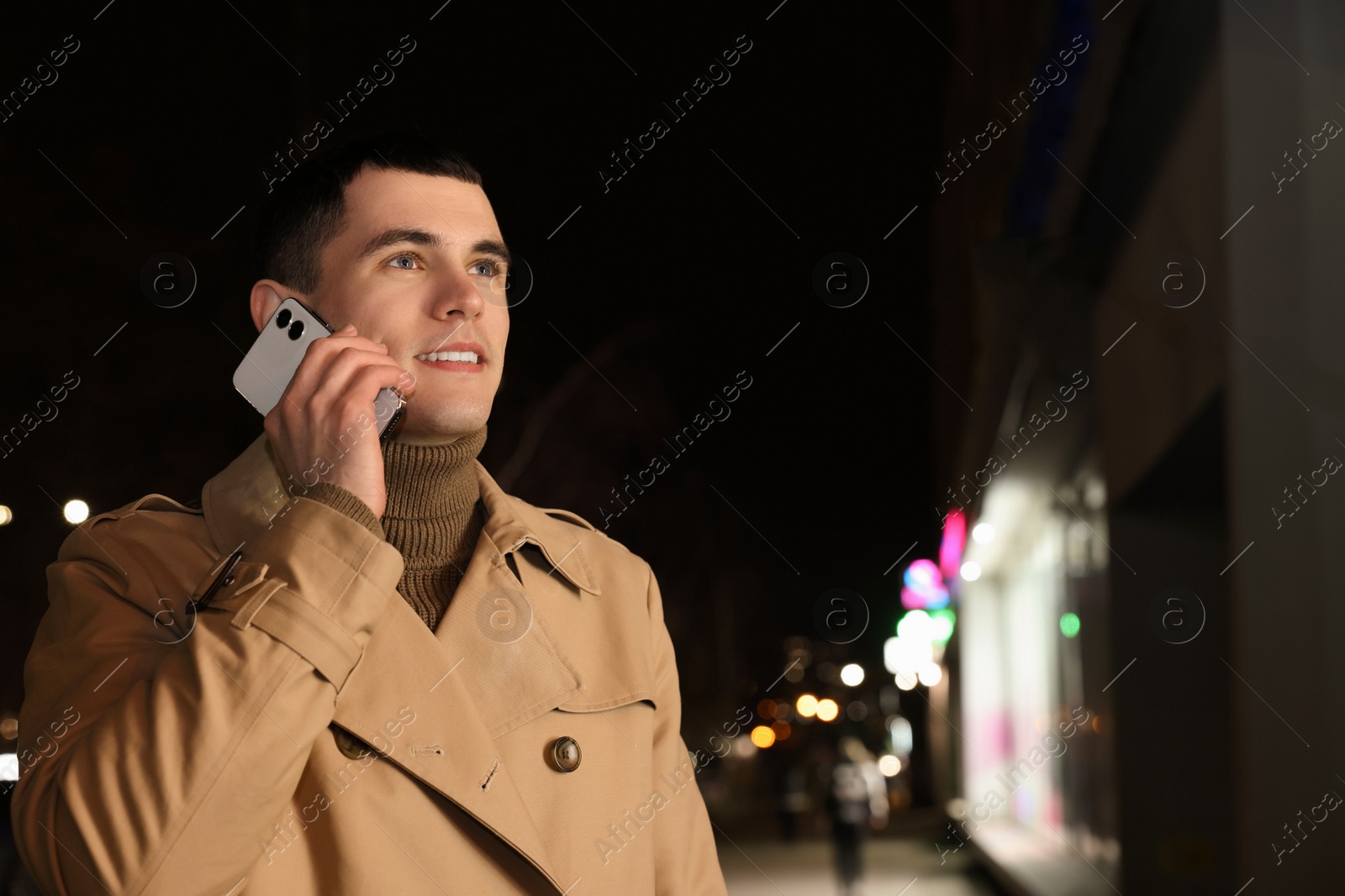 Photo of Man talking by smartphone on night city street, space for text