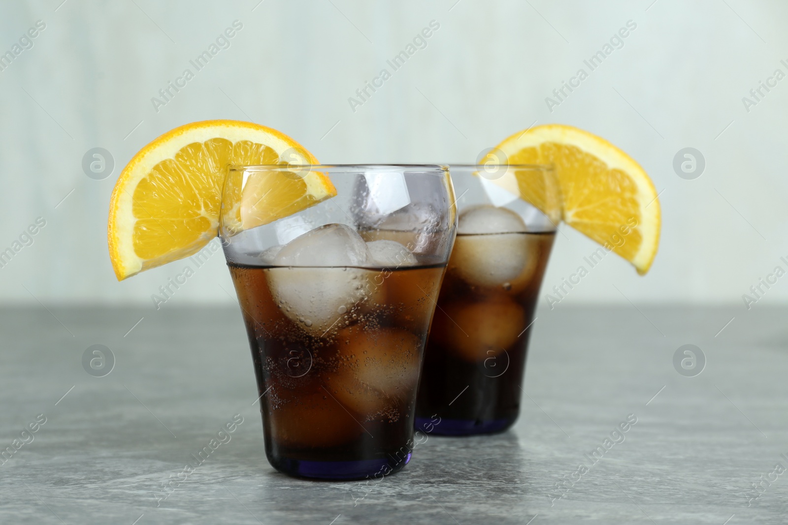 Photo of Delicious cocktails with orange and ice balls on grey table