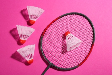 Badminton racket and shuttlecocks on pink background, flat lay