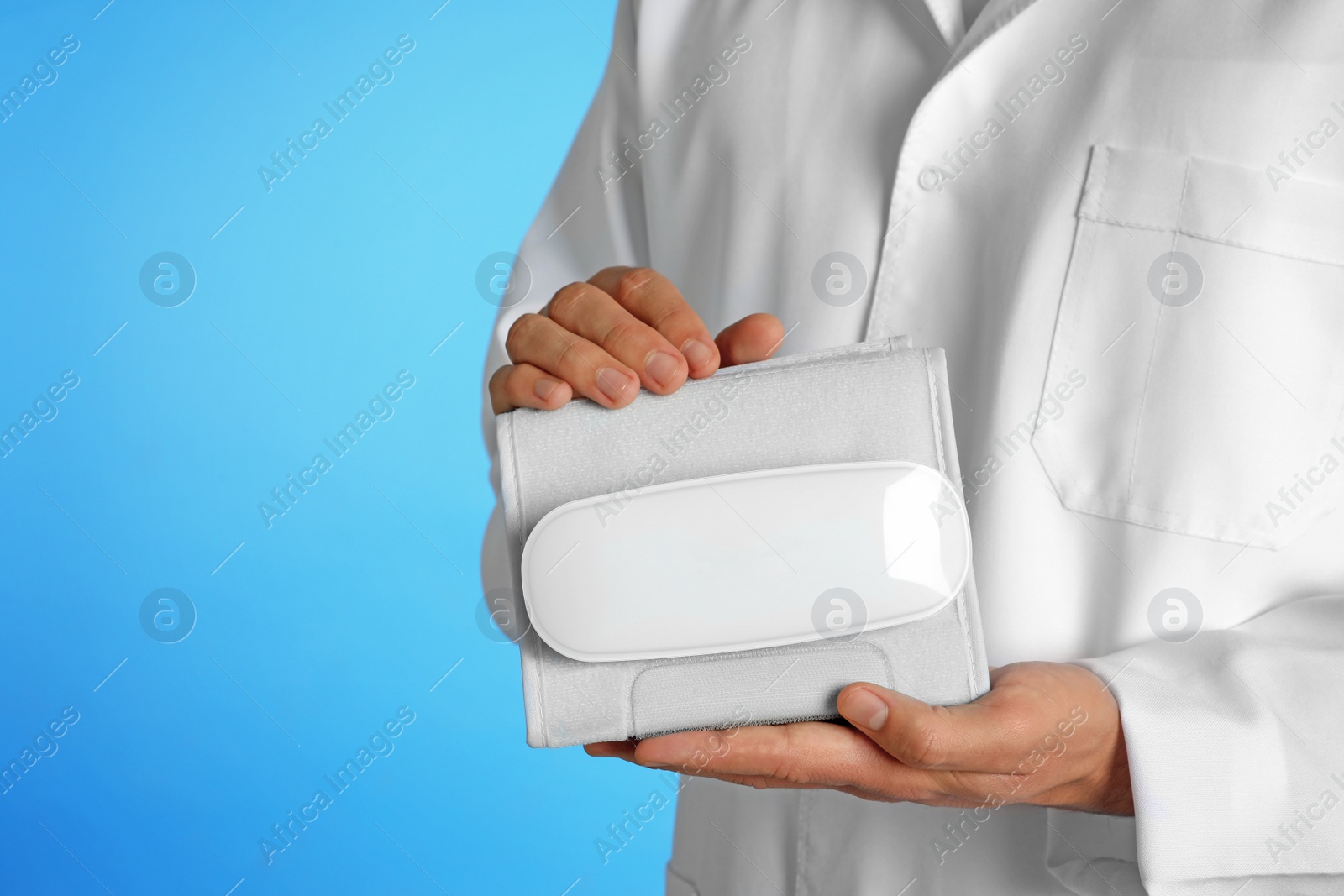 Photo of Male doctor holding blood pressure meter on color background, closeup. Medical object