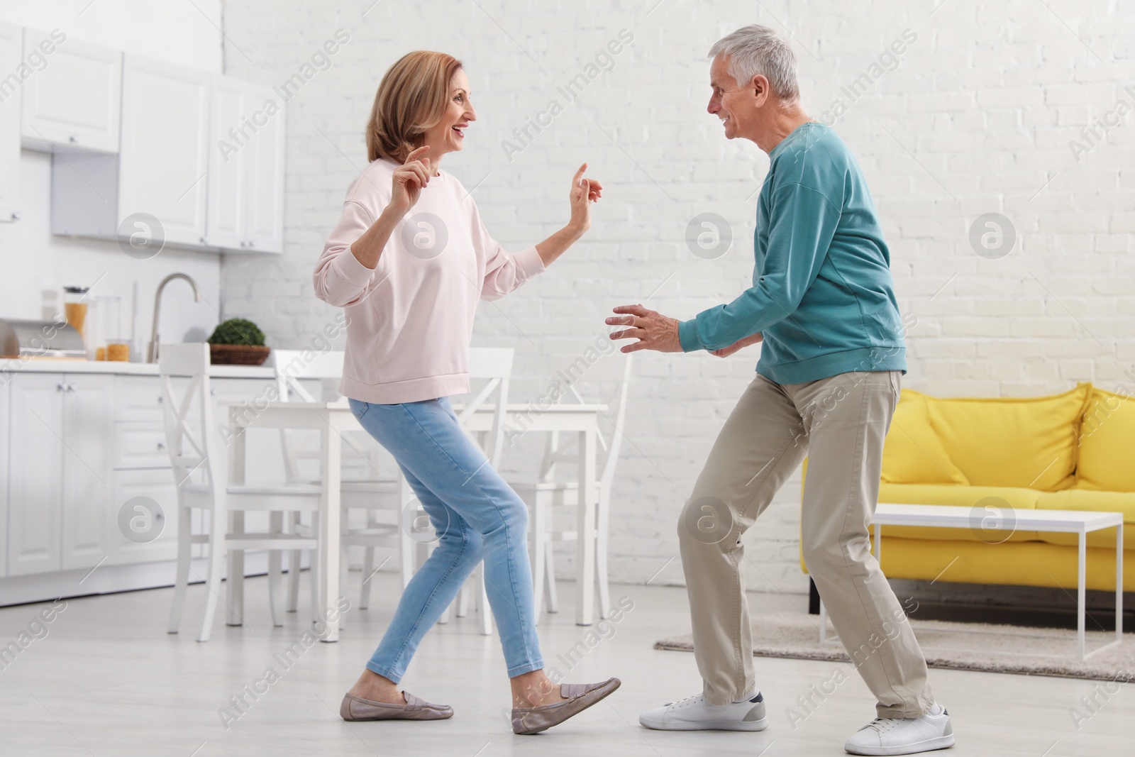 Photo of Happy senior couple dancing together in kitchen