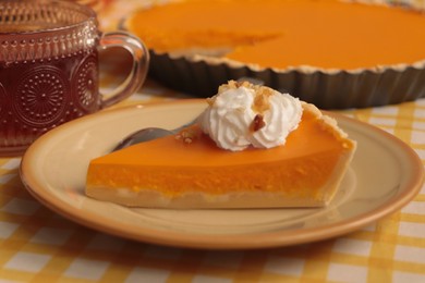 Piece of fresh homemade pumpkin pie served with whipped cream and tea on table, closeup