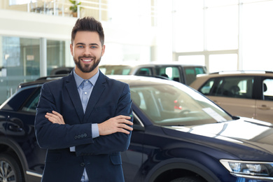 Photo of Happy young salesman in modern car salon