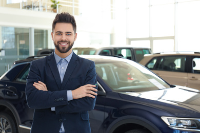 Happy young salesman in modern car salon