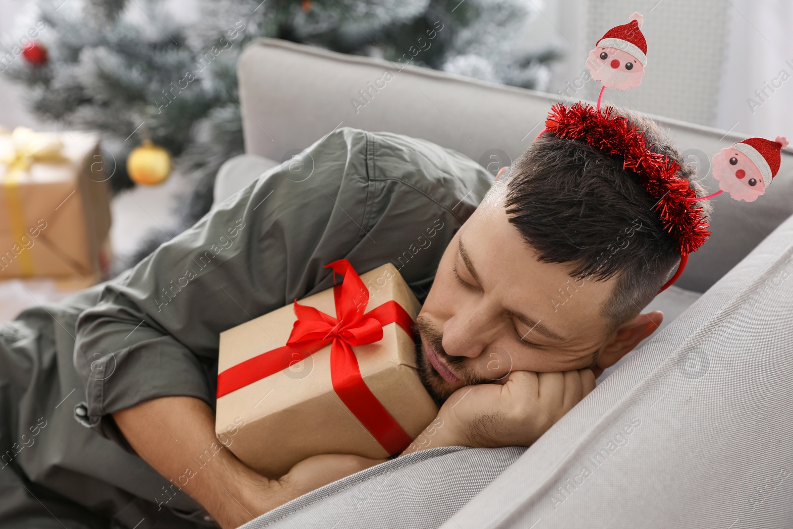 Photo of Man with gift box sleeping on sofa after New Year party