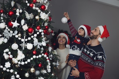 Photo of Happy family decorating Christmas tree together at home