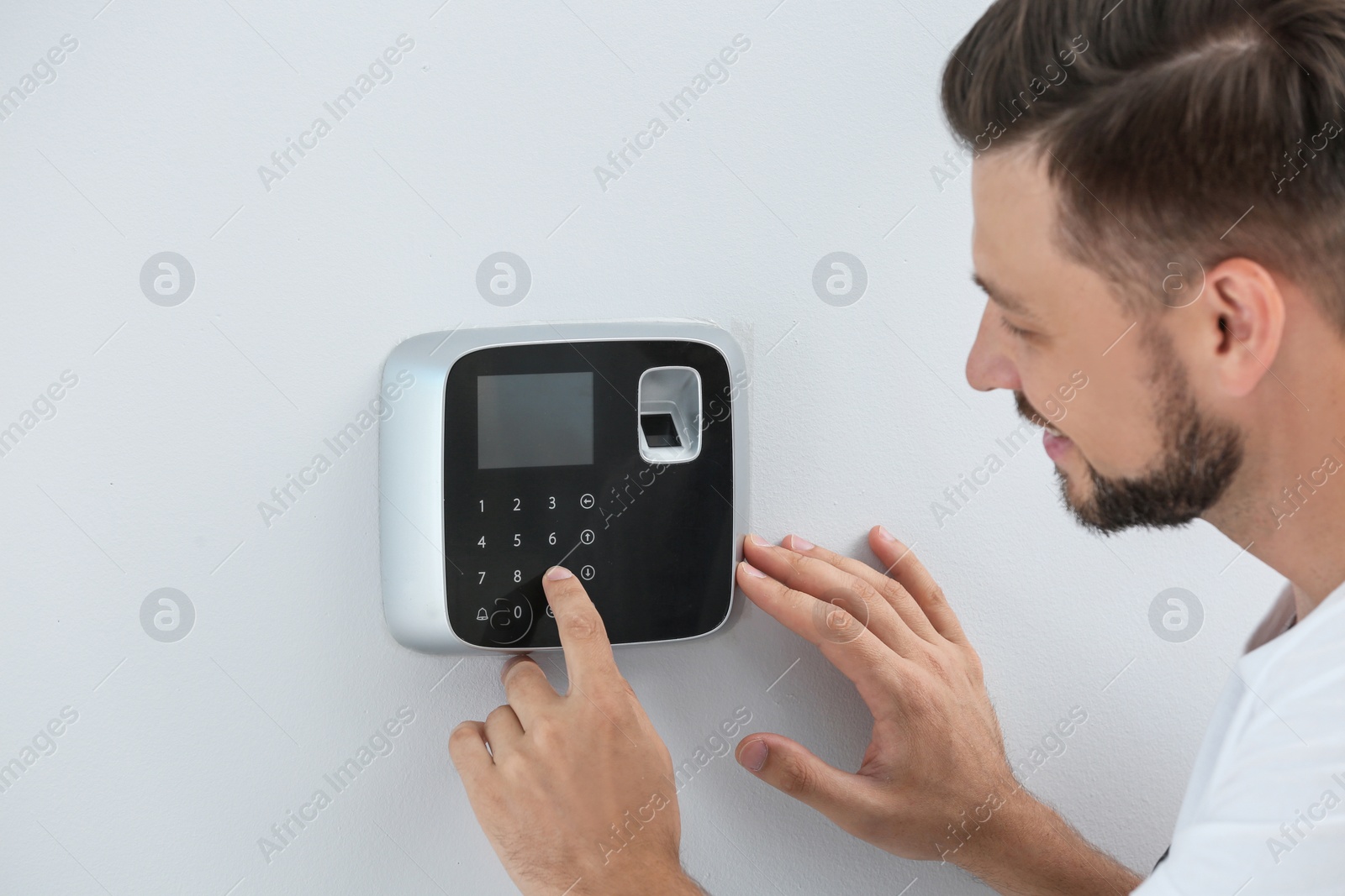 Photo of Male technician programming alarm system indoors