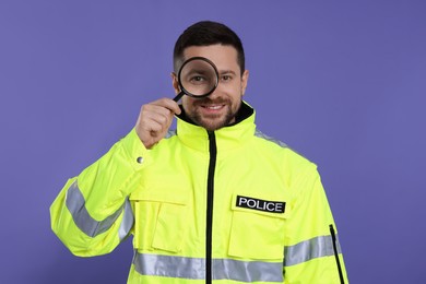 Smiling policeman looking through magnifier glass on violet background