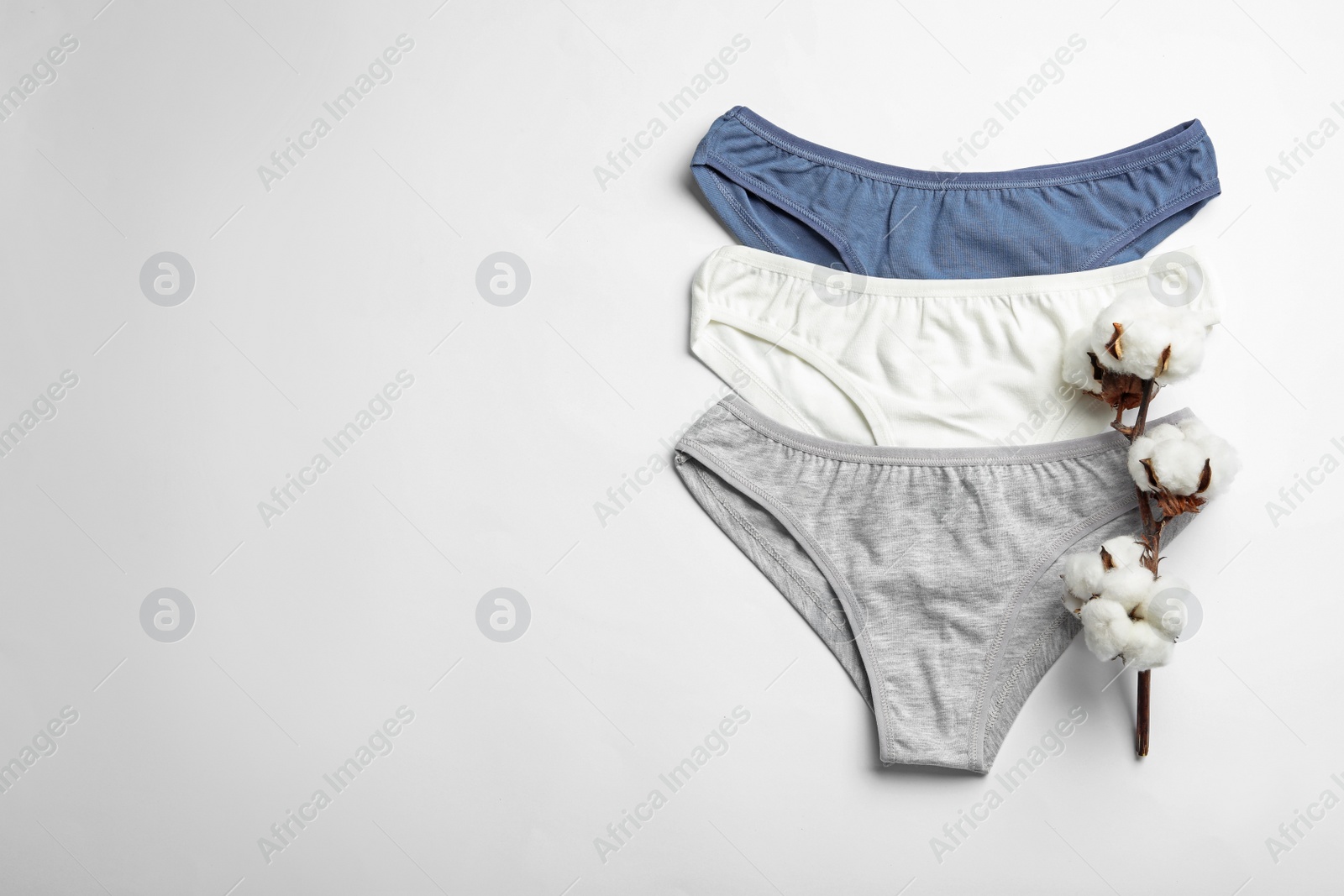 Photo of Comfortable women's underwear and cotton flowers on light background, flat lay