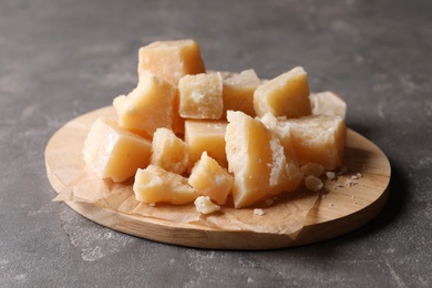 Parmesan cheese with wooden board on grey table, closeup