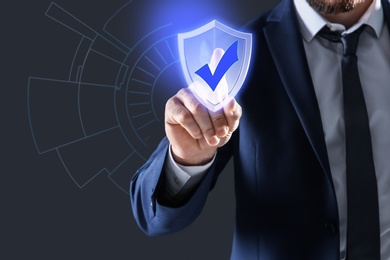 Cyber insurance concept. Man using virtual screen with shield illustration as symbol of protection, closeup