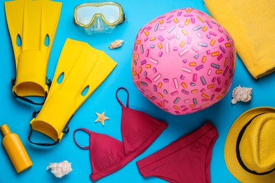 Photo of Flat lay composition with beach ball and swimsuit on light blue background