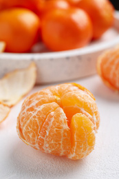 Photo of Peeled ripe tangerine on white table, closeup
