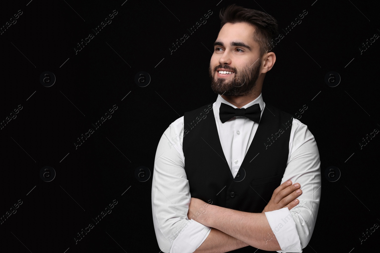 Photo of Portrait of smiling man in shirt and bow tie on black background. Space for text