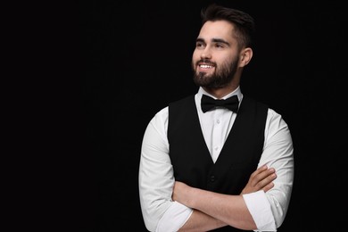 Photo of Portrait of smiling man in shirt and bow tie on black background. Space for text