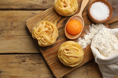 Photo of Raw noodles and ingredients on wooden table, flat lay