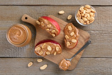Photo of Slices of fresh apple with peanut butter and nuts on wooden table, flat lay