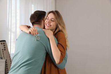 Photo of Happy young couple with key hugging in new house. Space for text