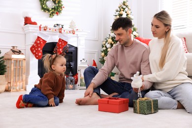 Happy family with gifts in room decorated for Christmas