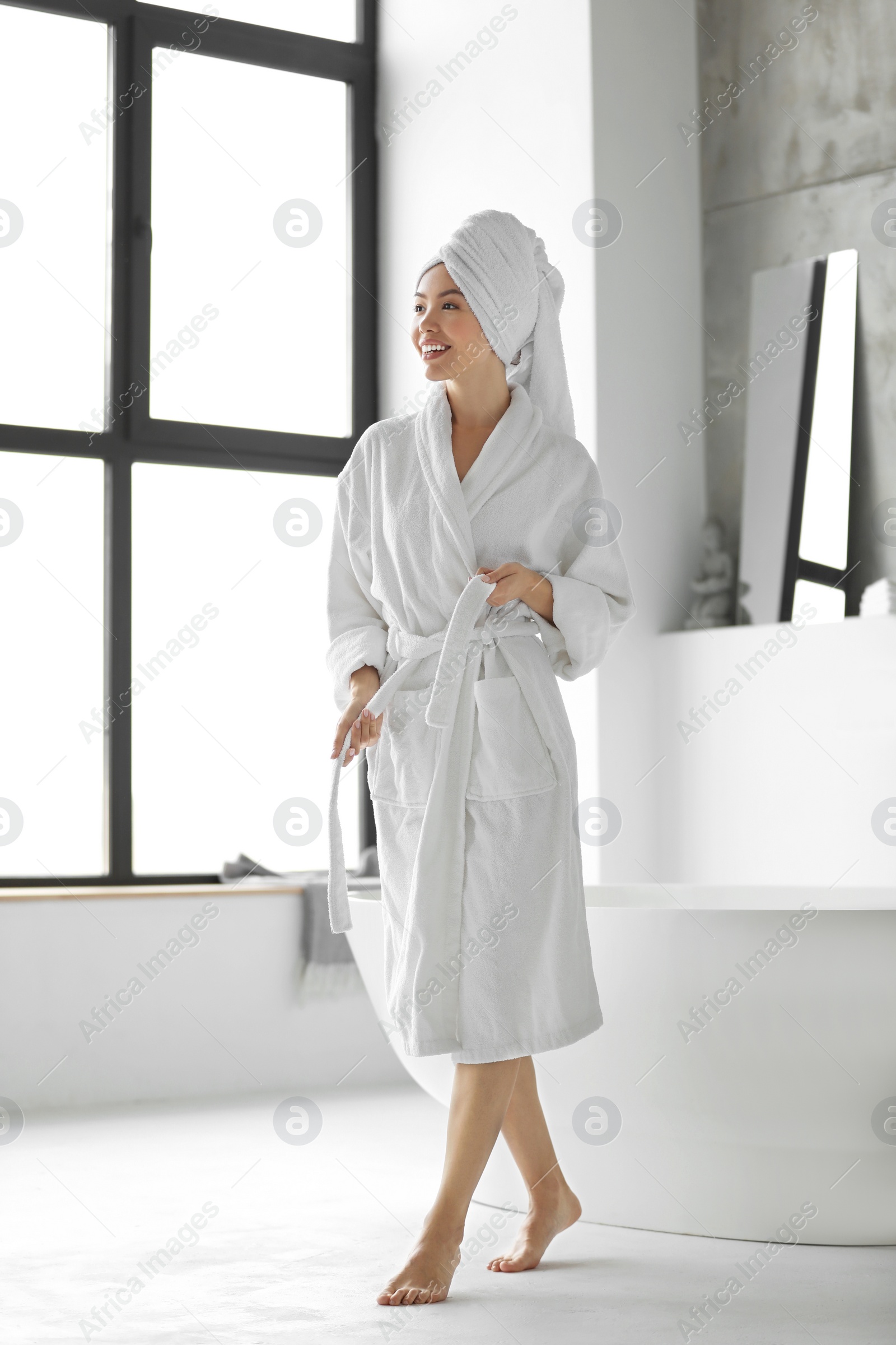 Photo of Young woman with towel in light bathroom
