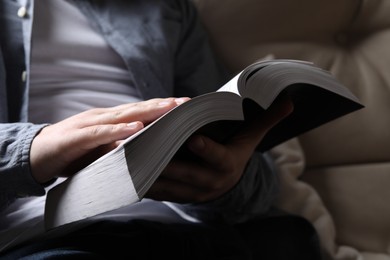Photo of Man reading holy Bible on sofa, closeup