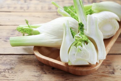 Photo of Fresh raw fennel bulbs on wooden table, closeup