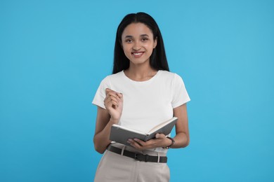 Photo of Beautiful secretary with notebook and pen on light blue background