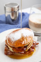 Photo of Delicious pancakes with maple syrup, sugar powder and fried bacon on plate, closeup