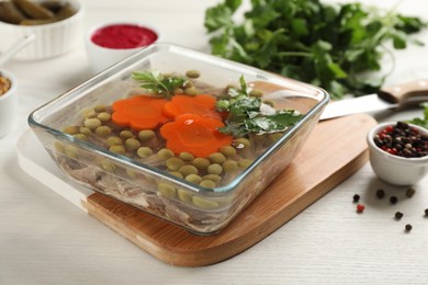 Photo of Delicious aspic in glass bowl on white wooden table