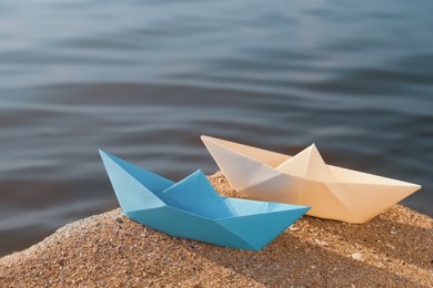 Photo of Two paper boats near river on sunny day