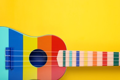 Colorful ukulele on yellow background, top view with space for text. String musical instrument
