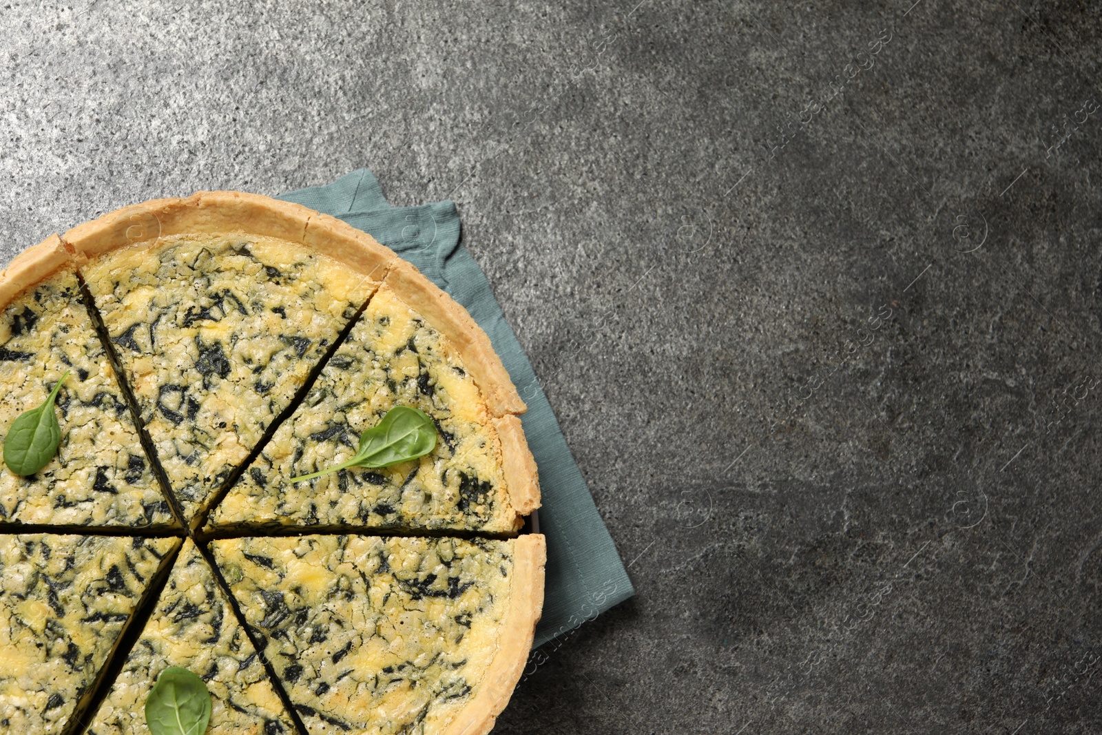 Photo of Cut delicious spinach pie on grey table, top view. Space for text