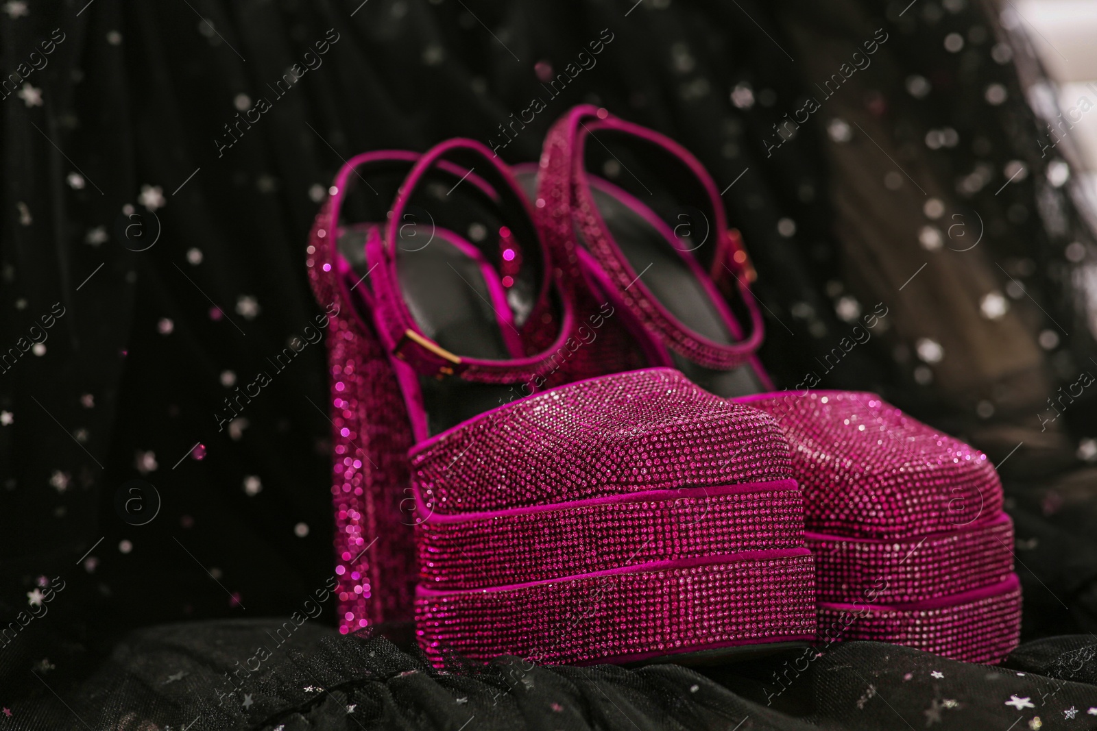 Photo of New pink high heeled shoes with platform and square toes on black cloth, closeup